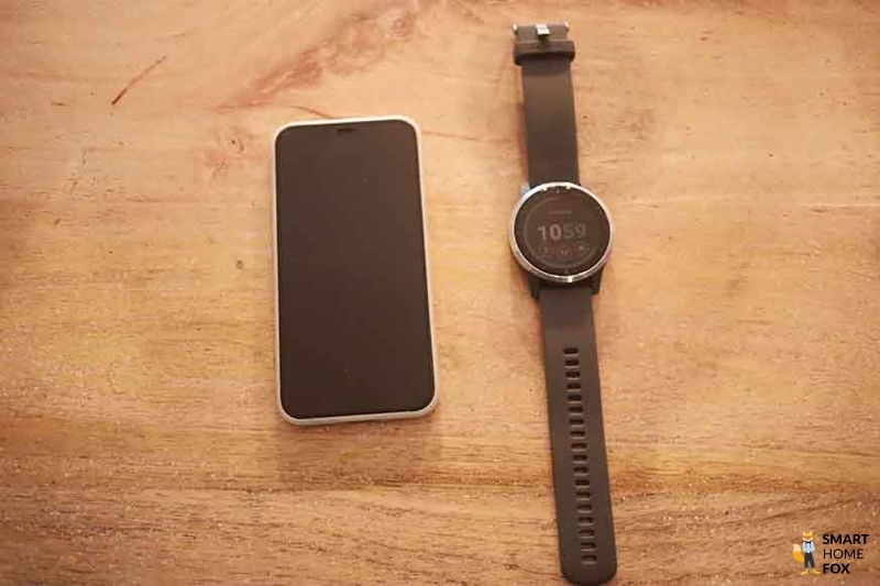 You can see a smartwatch lying next to a mobile phone on the table.